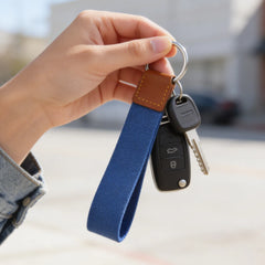 Hand holding a keychain with a blue strap and car keys.