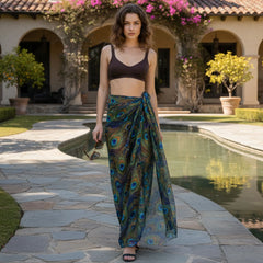 Woman in a peacock-patterned sarong standing by a poolside.