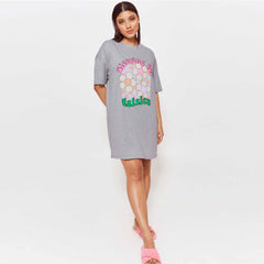 wearing a grey oversized T-shirt dress featuring colorful daisy graphics and the text 'Sleeping in Daisies.