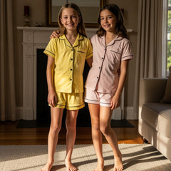 Two children in matching pajama sets standing in a cozy living room.