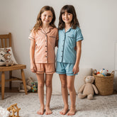 Two children wearing matching pajama sets in a room with toys and furniture.