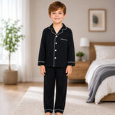 Child wearing black pajamas with white buttons in a bedroom setting