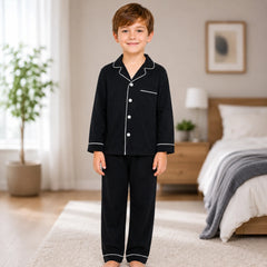 Child wearing black pajamas with white buttons in a bedroom setting