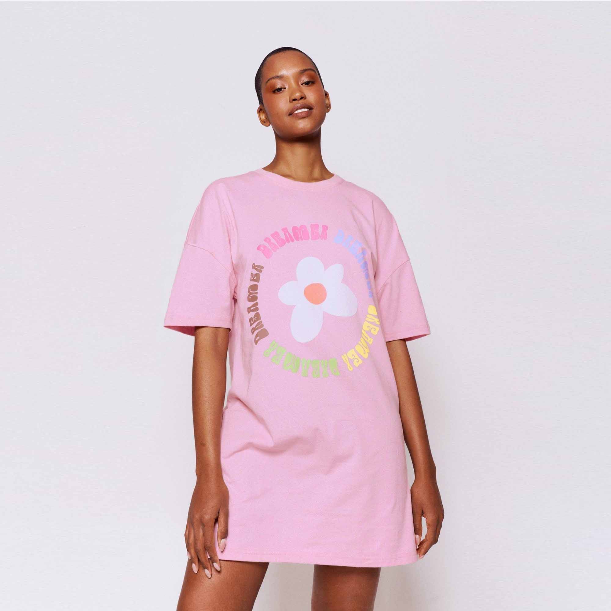 wearing a grey oversized T-shirt dress featuring colorful daisy graphics and the text 'Sleeping in Daisies.