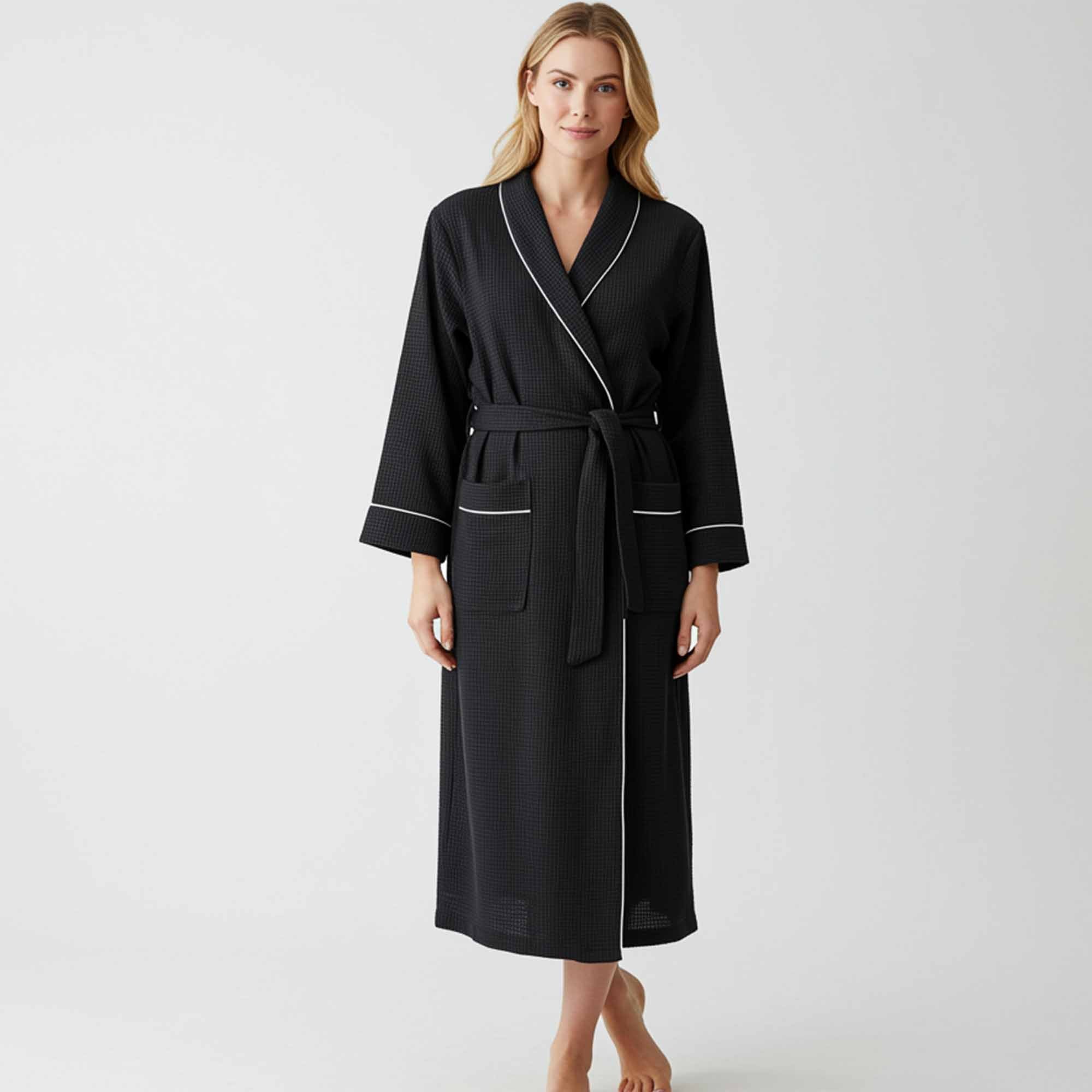 Woman wearing a black full-length robe with white piping and a tie waist.
