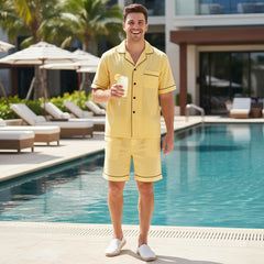 Man in yellow outfit standing by a pool holding a drink