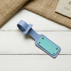 Blue and green leather luggage tag on a wooden surface