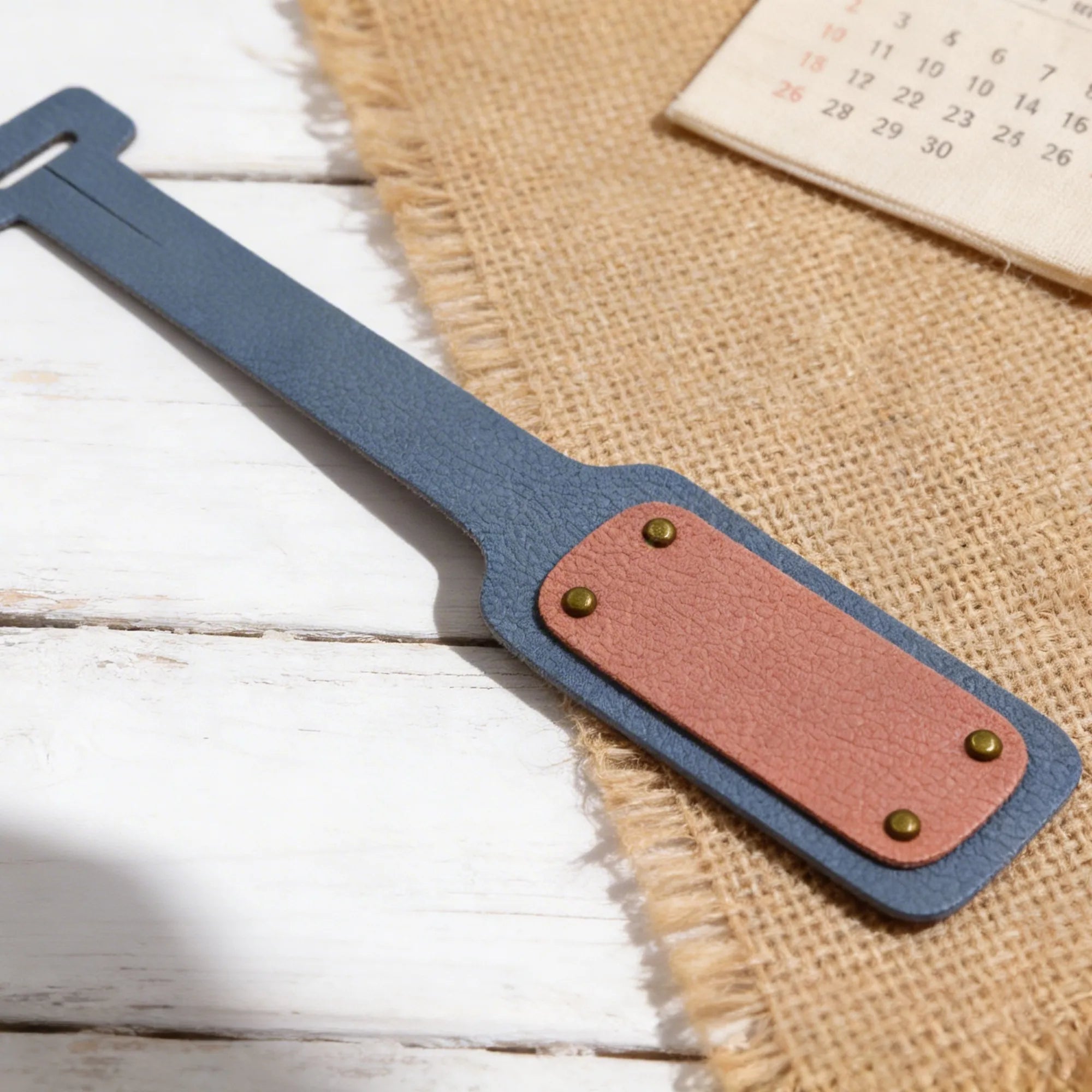 Blue and pink leather strap with metal studs on a wooden surface