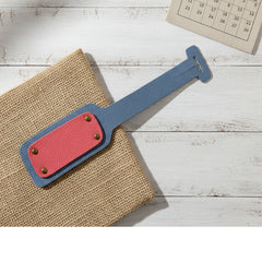 Blue and red leather strap on a textured surface with a calendar in the background