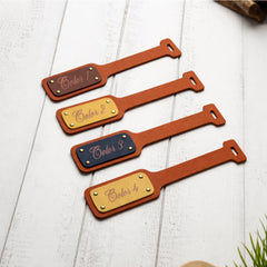 Four leather name tags with color labels on a white wooden surface