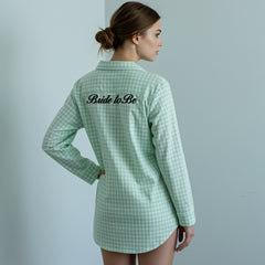 Woman in mint green gingham nightshirt with black Bridesmaid embroidery in a kitchen setting