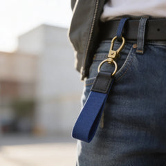 Person wearing a blue keychain with a gold clasp on jeans.