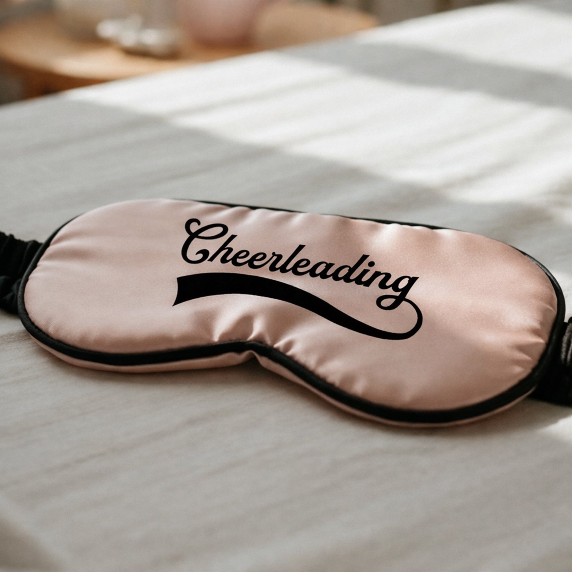 Pink sleep mask with 'Cheerleading' text on a white surface