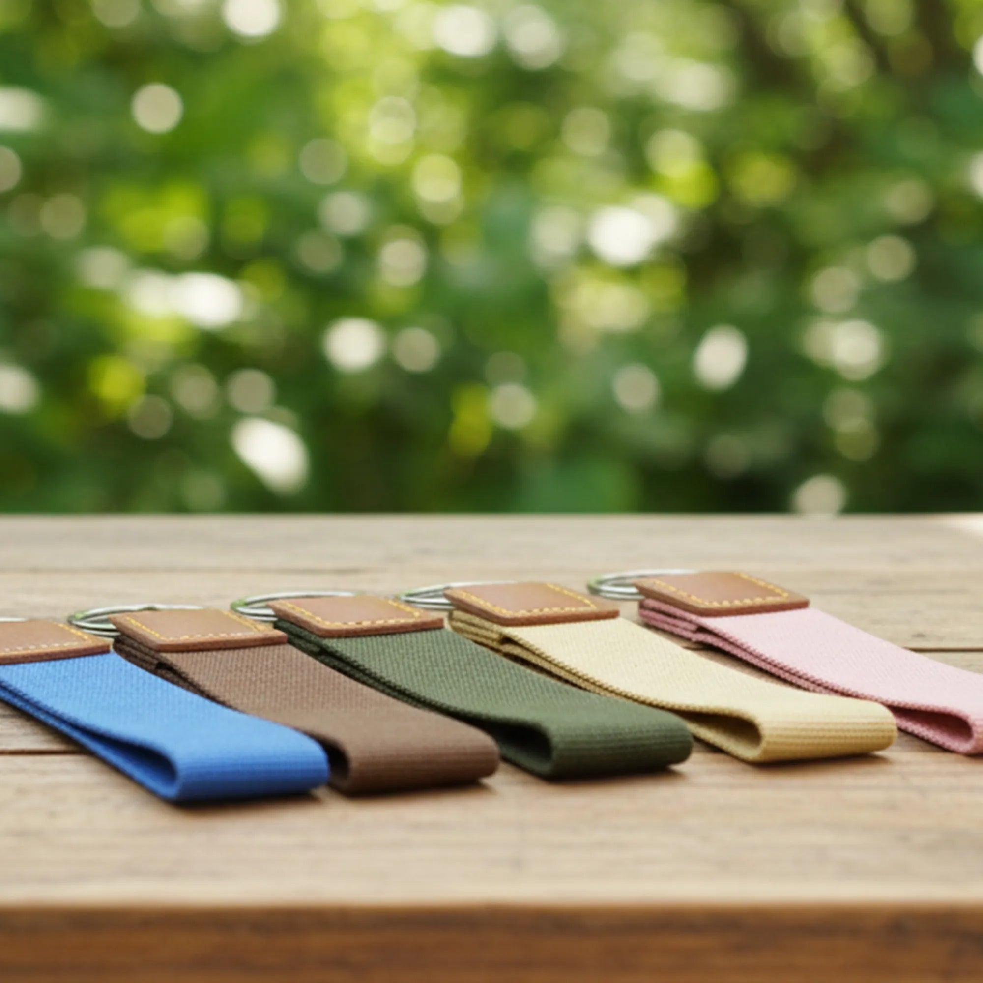 Set of colorful keychains on a wooden surface with a blurred green background