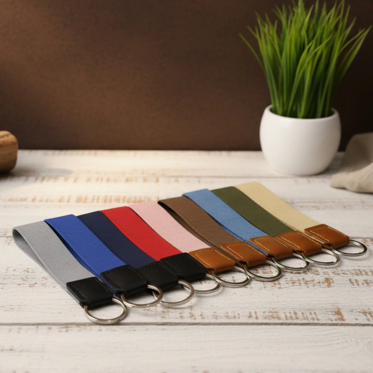 Set of keychains with colorful straps on a wooden surface with a plant in the background