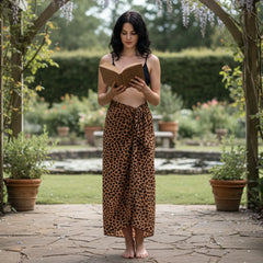Woman in black bikini top and leopard print skirt standing in a store with baskets and bags in the background.