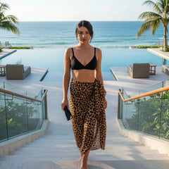 Woman in black bikini top and leopard print skirt standing in a store with baskets and bags in the background.