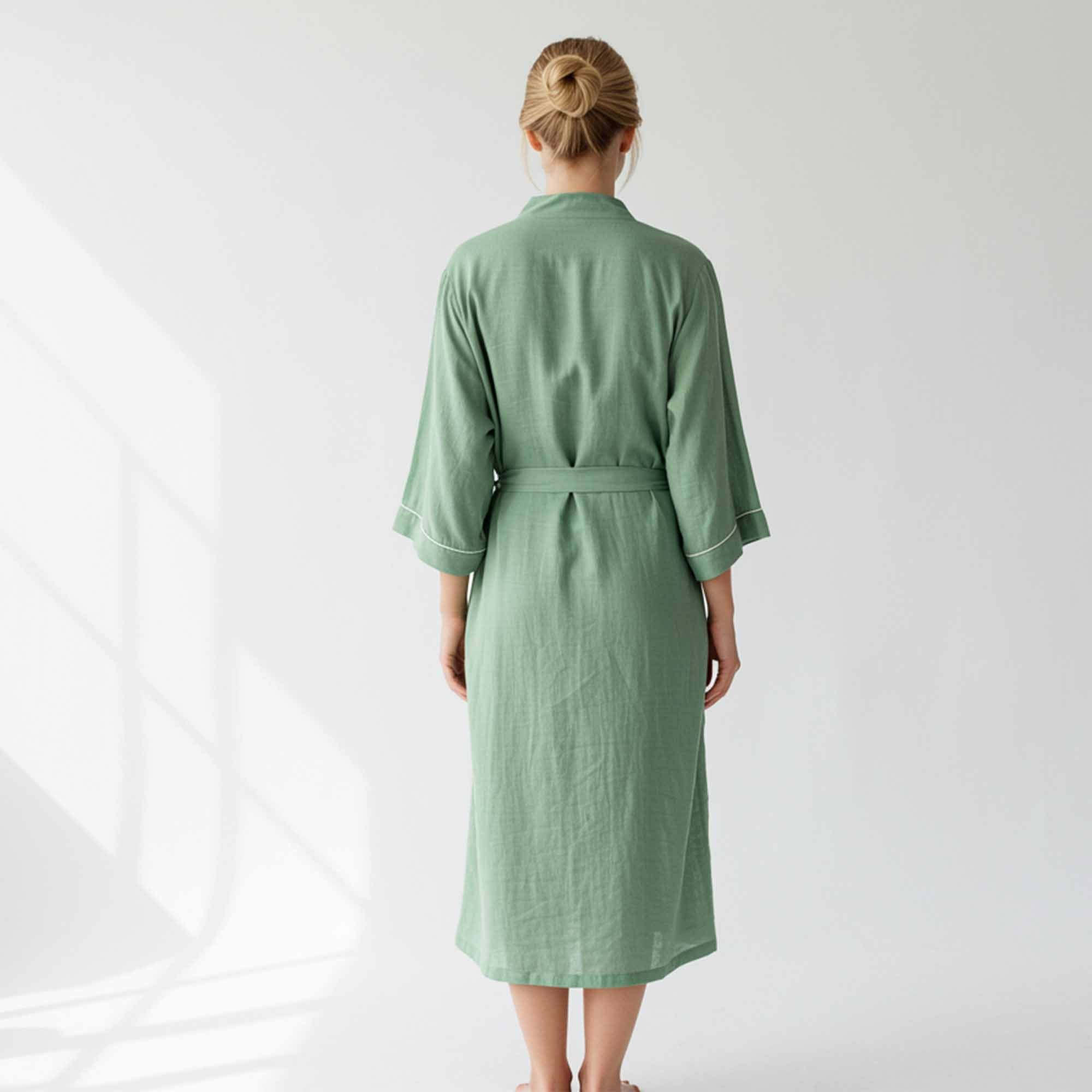 woman wearing a sage green long cotton lounge robe with a waist belt.