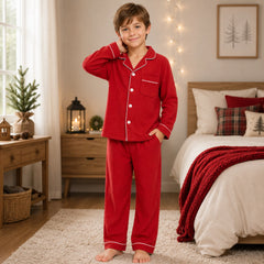 Child wearing red pajamas in a cozy bedroom with Christmas decorations.