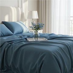 Deep midnight blue satin sheets featuring a luxurious draped texture on a white bed frame