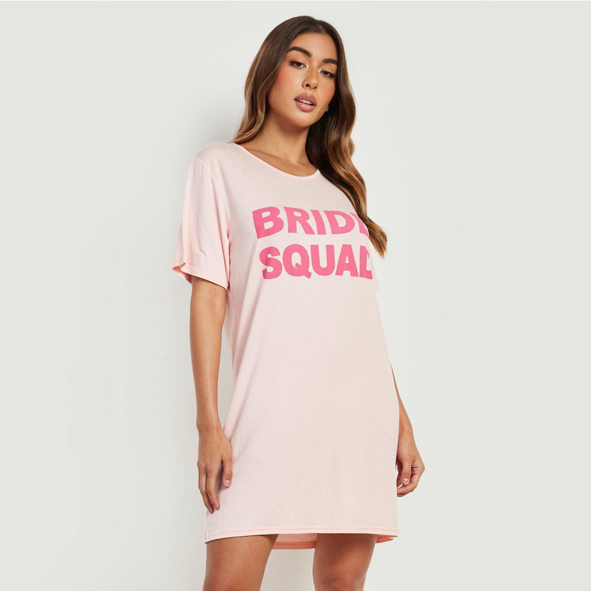 wearing a light pink nightdress with bold pink ‘Bride Squad’ text on the front.