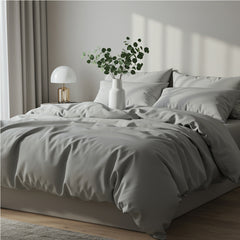 Premium slate grey satin duvet cover and sheet set styled with a white lamp and greenery